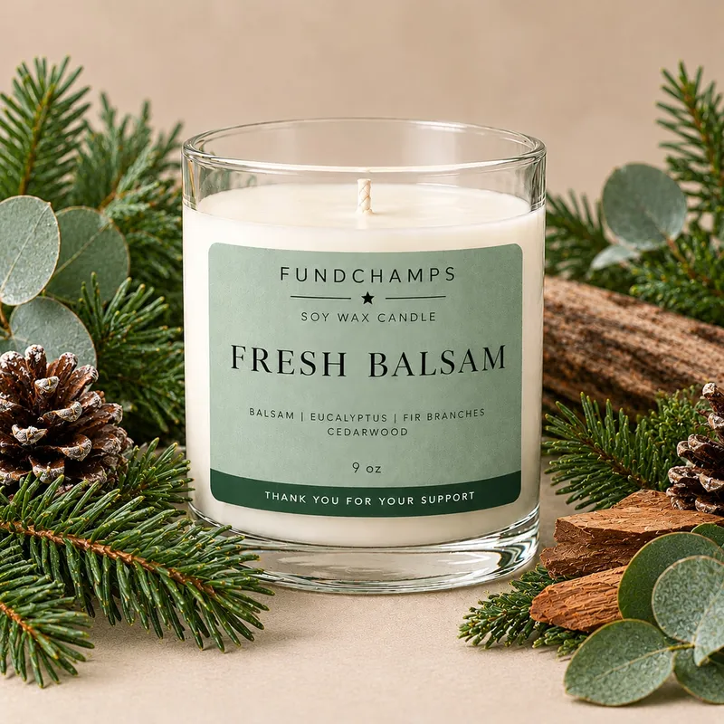 A FundChamps Fresh Balsam soy wax candle surrounded by fir branches, pine cones and eucalyptus